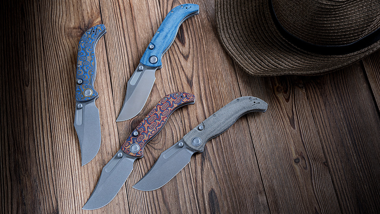 Four folding knives with different handle materials and colors are displayed on a wooden background next to a brown fedora-style hat