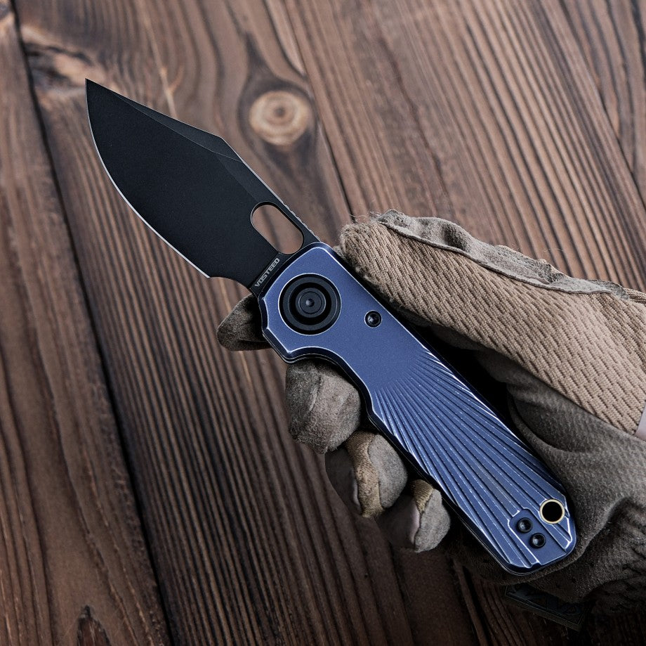Vosteed Akita knife with blue handle and black blade on hand