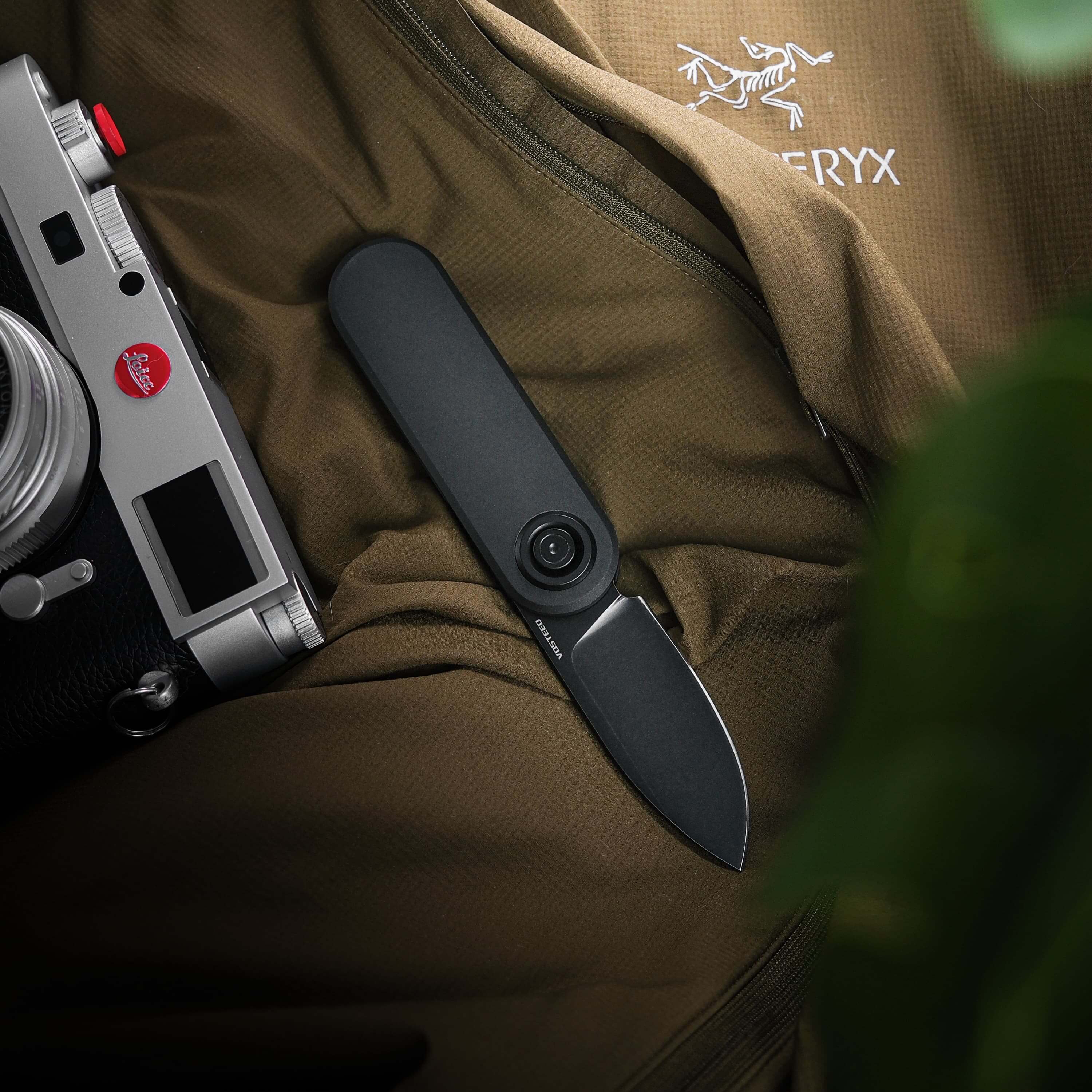 Vosteed Corgi V black knife with Leica camera and Arc'teryx apparel