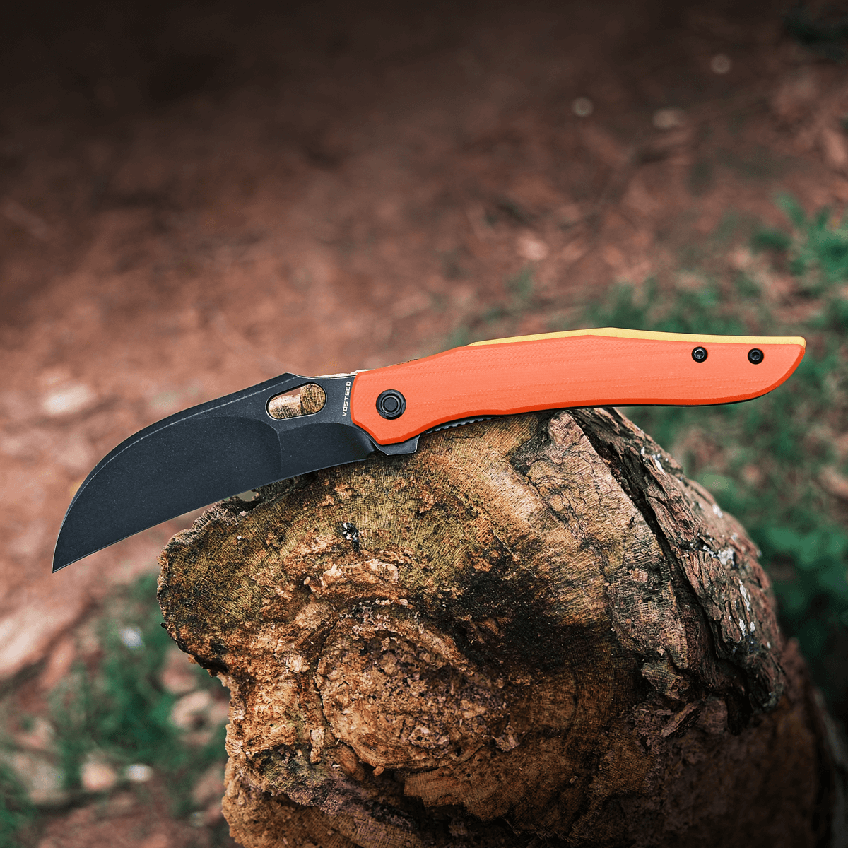 Vosteed Griffin hawkbill knife on wood, black blade, orange handle