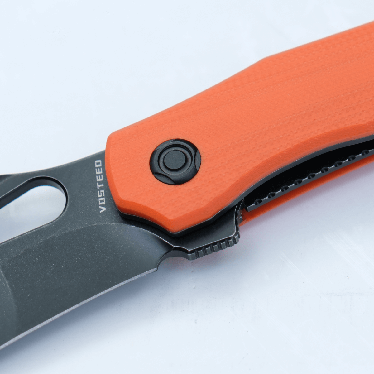 Vosteed Griffin knife detail, black blade with orange G10 handle.