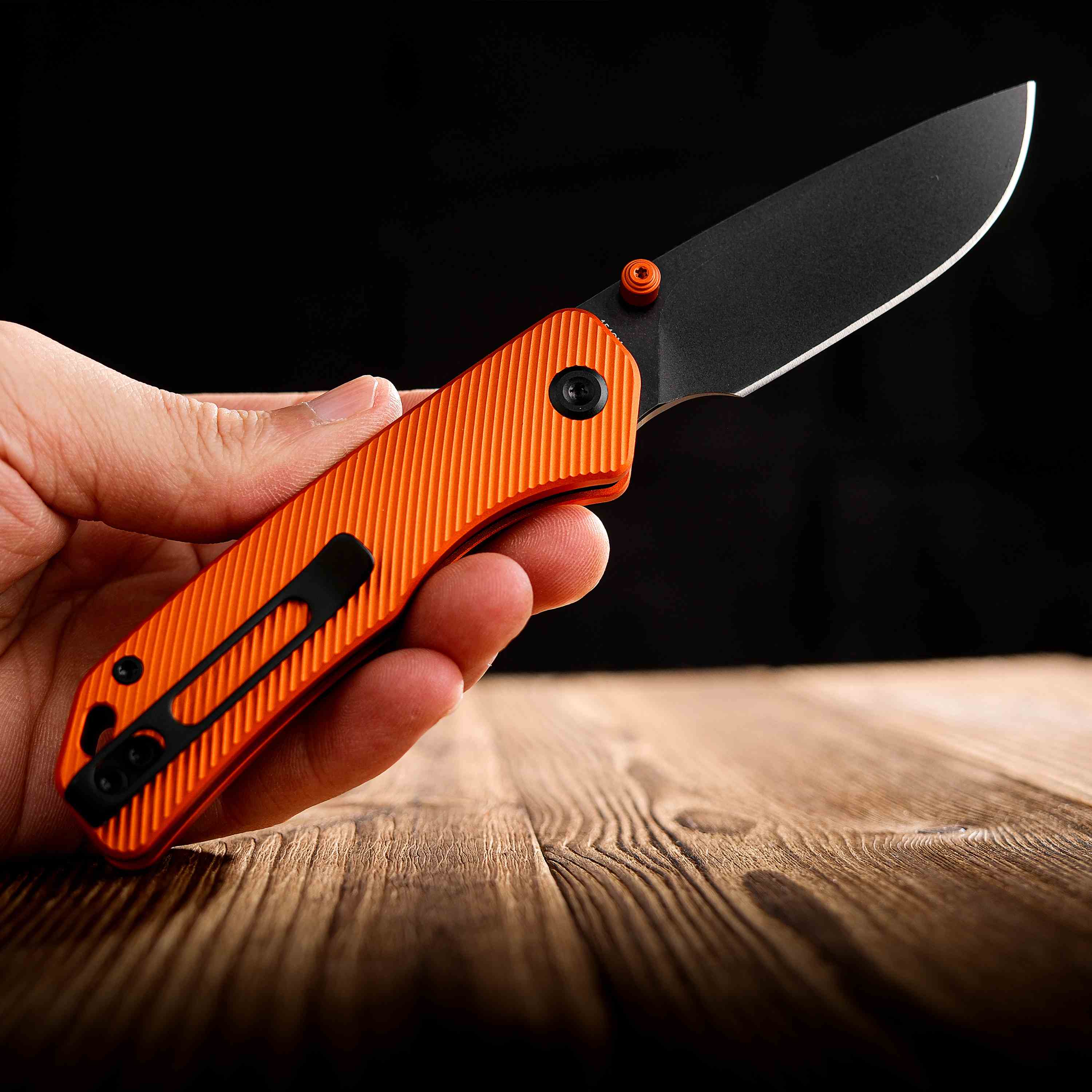 Vosteed Marten knife held in hand, orange handle and black blade