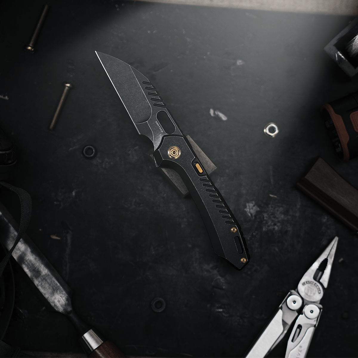 Vosteed RSKAOS Knife on workbench, black titanium with gold accents