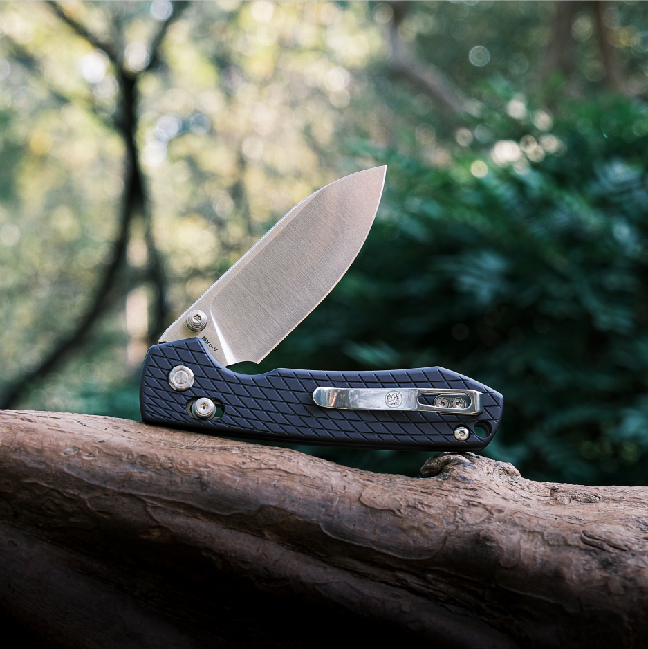 Vosteed Raccoon knife with blade open on wood, in nature