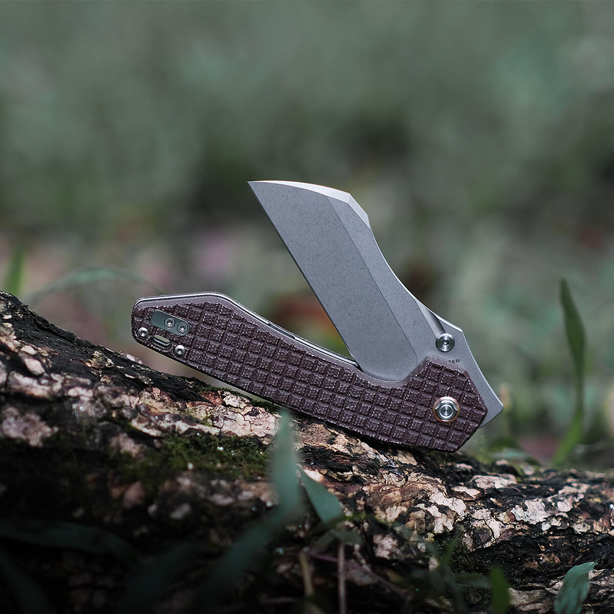 Vosteed Gator knife with Micarta handle, open blade on a log